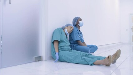 Sleepy afro-american female doctors sitting on floor, exhausted by overwork