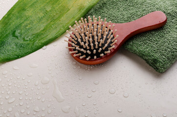 Closeup of wooden brush, green topical leaf and towel on the empty beige surface