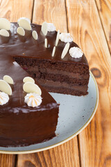 Cut chocolate cake on plate on wooden table