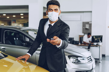 Man car dealer wearing protective medical mask on his working place