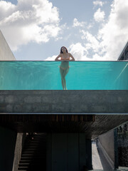 asian woman in bikini in infinity swimming pool edge. luxury vacation near the sea.