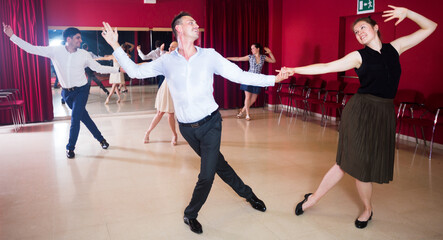 Adult dancing couples enjoying active boogie-woogie in modern studio