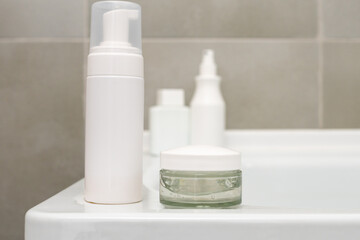 white containers with cosmetics in the bathroom with gray walls. Spa. Body care.