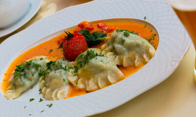 Image of traditional polish dumplings with mashed potato and tomato at plate