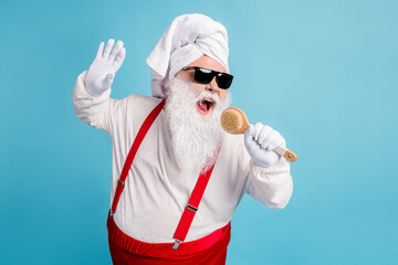 Fototapeta na wymiar Photo of pensioner old fat man grey beard hold body brush sing shower pretend hold mic play funny game wear santa x-mas costume towel turban suspender sunglass isolated blue color background