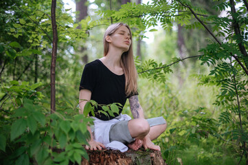 Practice of meditation and interaction with nature. Girl in green forest