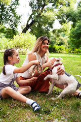 young pretty caucasian mother walking with little cute daughter and dog fox terrier, lifestyle people concept