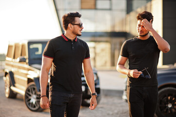 Two asian brothers man wear on all black posed near suv cars.