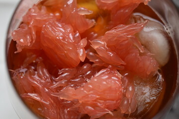 Fresh pink grapefruit, pomelo fruit with iced black tea. Top close up