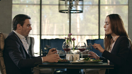 Happy couple dining in restaurant. Woman taking food from man plate at dinner
