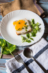 Top view of fried eggs with bacon and bread in a white plate with condiments