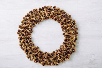 Top view of gold color pine cone wreath. Minimalist Christmas background with a lot of copy space.