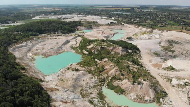 Drone view on a flooded kaolin quarry with turquoise water and white shore. Aerial survey of a kaolin pit flooded with water.