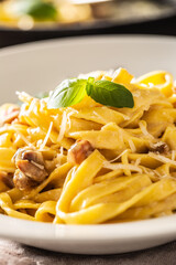 Italian food pasta tagliatelle carbonara with pancetta parmesan egg yolk and basil leaves