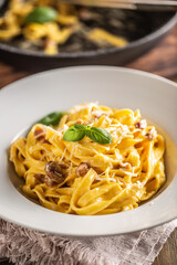 Italian food pasta tagliatelle carbonara with pancetta parmesan egg yolk and basil leaves