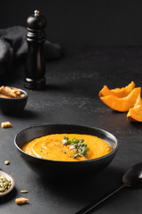 Pumpkin soup garnish microgreens on black background. Close up. Vertical format.