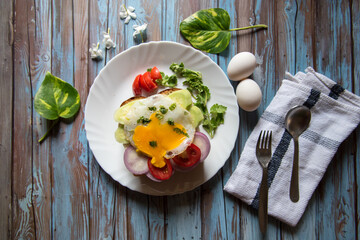 Top view of salad with eggs and cheese on bread along with condiments on a white plate