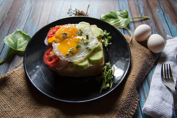Close up of egg poach, salad condiments on bun bread with use of selective focus
