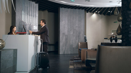 Businessman with travel suitcase arriving in hotel at holiday