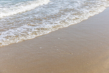White bubbles from sea wave at a clean tropical beach on sunny day