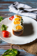 Close up of sliced boiled eggs on bacon with condiments
