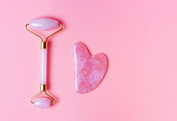 The gua sha and the face roller on pink background, copy space © TATIANA KIM