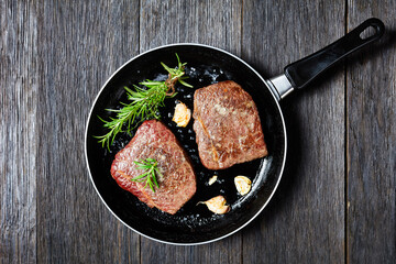 fried beef steaks on a skillet, top view