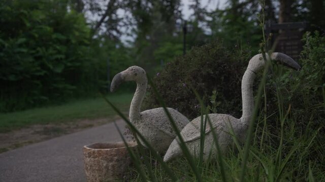 Flamingo sculptures standing in vegetation next to lake or outdoor camping site