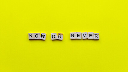 Words "Now or never" on a yellow paper background. Motivating web banner.