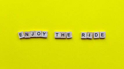 Words "Enjoy the ride" on a yellow paper background. Motivating web banner.