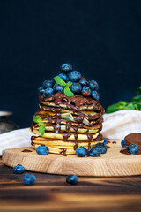 pancakes with chocolate and blueberries on a dark background