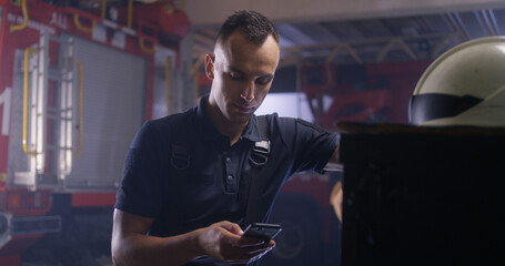 Fireman using smartphone and talking with colleague