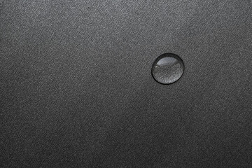 a drop of water on a dark surface close up