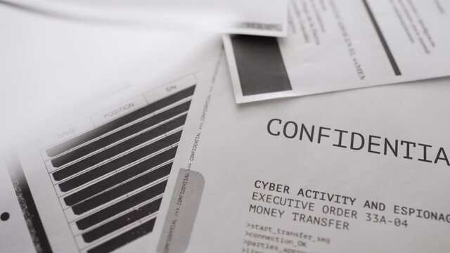 Secret paper document is left on a desk then taken out. Classified information. Documents and files in background with blacked out text lines or erased censored delicate government agency material.