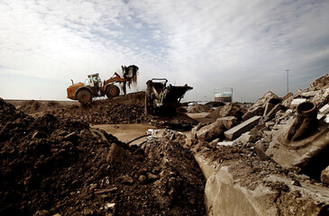 A constuction site in Denmark. Dirt and mud and a machine working on site. Cloudy sky.