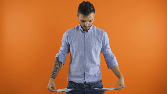Sad, desperate young man looking around showing empty pockets. Concept of no money. poor gesture