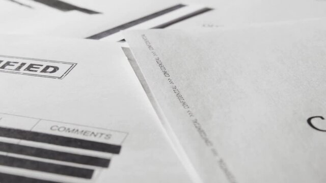 Pan across classified text documents and top secret censored information files. Leaked papers of covert activity and operations of military, army or government agencies. Close up of sensitive info.