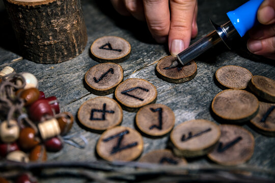 man writing wooden runes with an pyrography or pokerwork