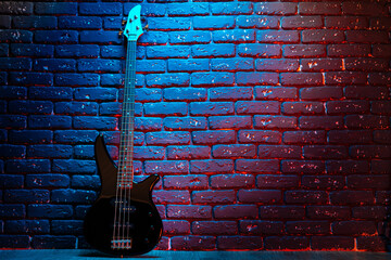 Fototapeta na wymiar Electric guitar in neon light against dark walll