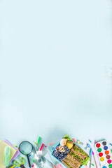 Fototapeta premium Healthy children school lunch box: sandwich, vegetables ,fruit and mineral water bottle, with school supplies on, on light blue background copy space