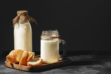 Glass of milk with sliced baguette on wooden board