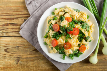 scrambled eggs with spinach and tomatoes on a white plate.