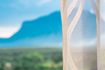 White curtain by the window and view of the mountain with light from the sunset, Beautiful curtain make the house more livable,The atmosphere of relaxation at living room in a holiday close to nature.