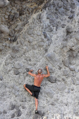 Man climbing a vertical cliff without safety measures, extreme sports