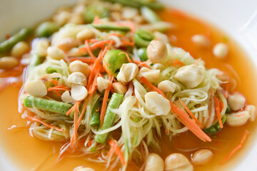 Thai food papaya salad with macadamia nuts on top on white plate Healthy food