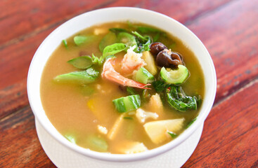 Thai Spicy Mixed Vegetable Soup with Prawns in bowl on wooden table , top view - Thailand food of Asian