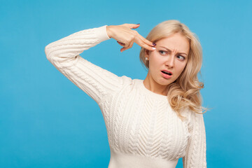 Upset tired of life blond woman holding fingers near head imitating gun, desire to commit suicide,...