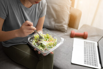 Young Asian woman eating vegetables salad after exercise at home