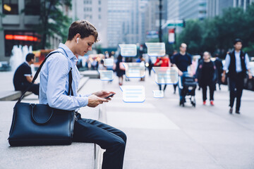 Side view of modern man messaging on phone on street