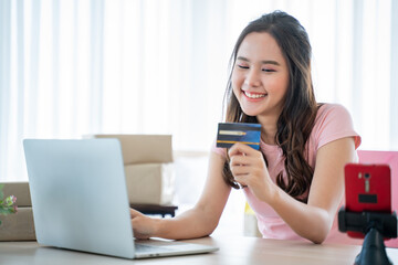 Online shopping and Digital Debit concept.Happy attractive woman doing online shopping with credit card at home.Young girl doing e-shopping and inputting card information in laptop.